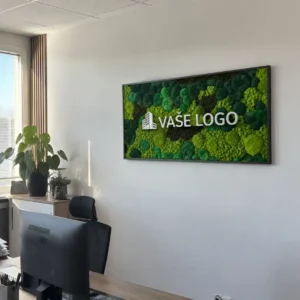 Vizualizácia machového obrazu Verdara s bielym nápisom „VAŠE LOGO“ v tmavom ráme pri kancelárskom okne, rastline a drevených lamelách.